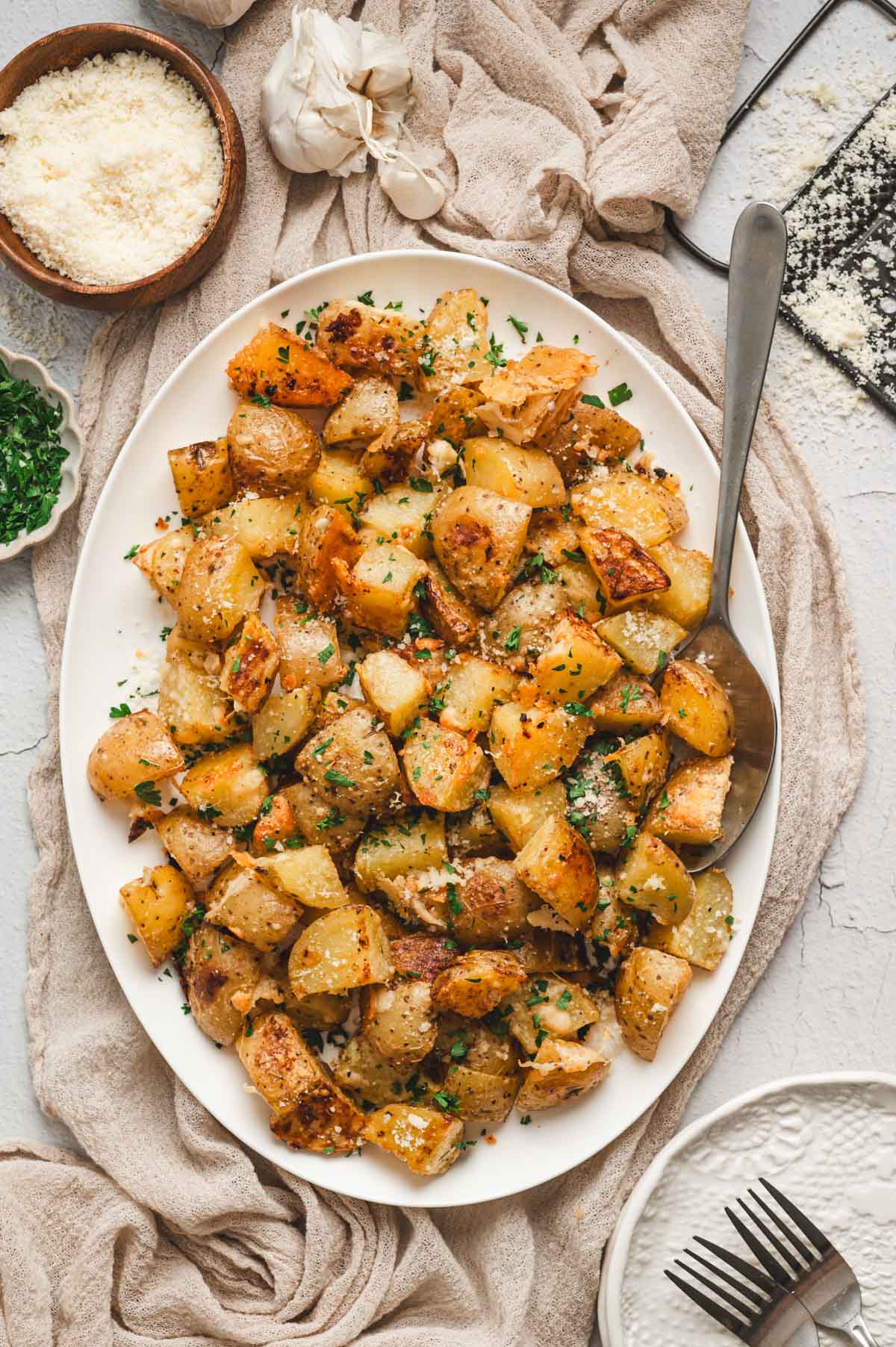 Diced roasted potatoes on a white platter with a serving spoon.