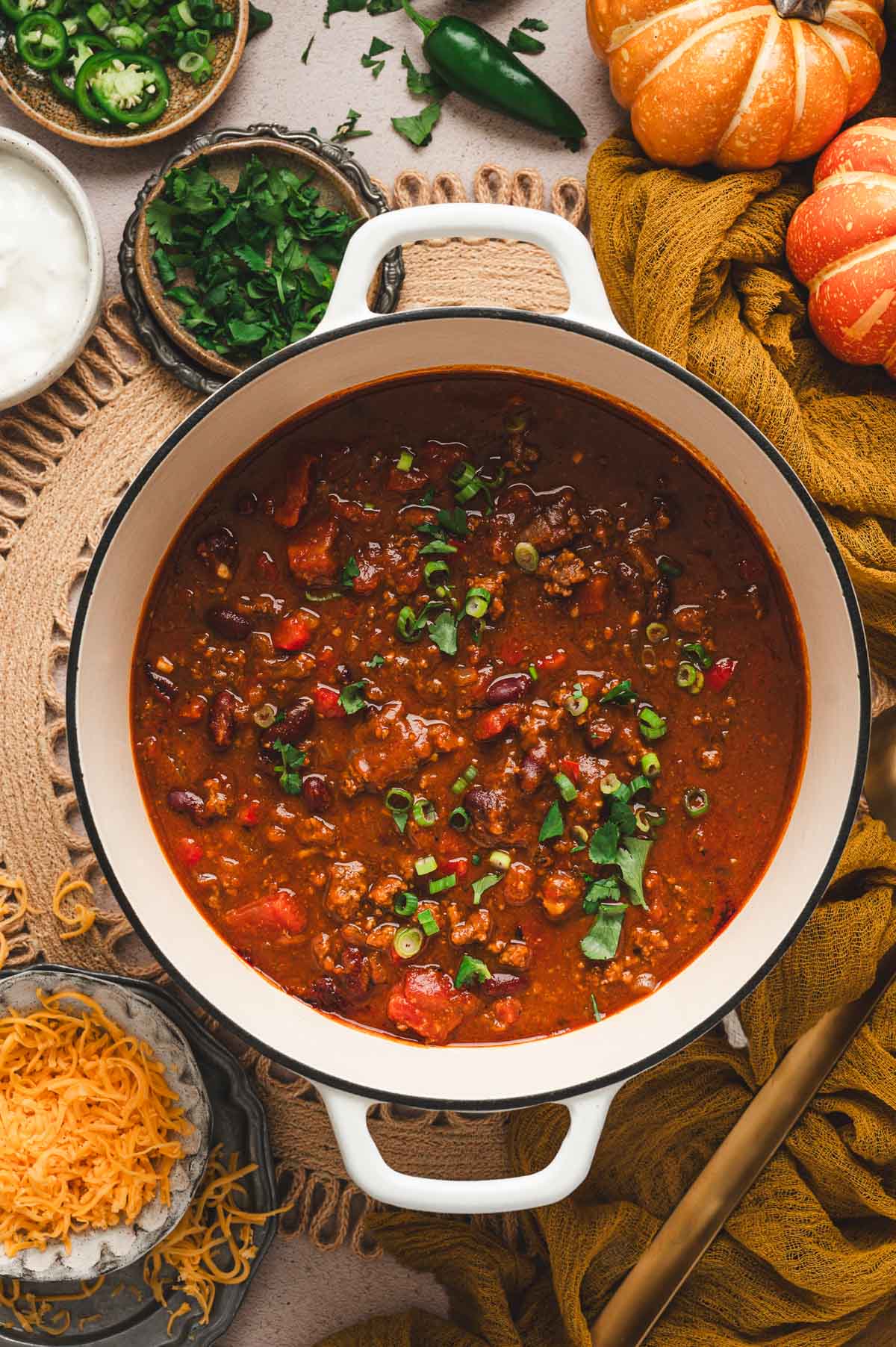 White pot with pumpkin chili and green onion and cilantro garnish on top.