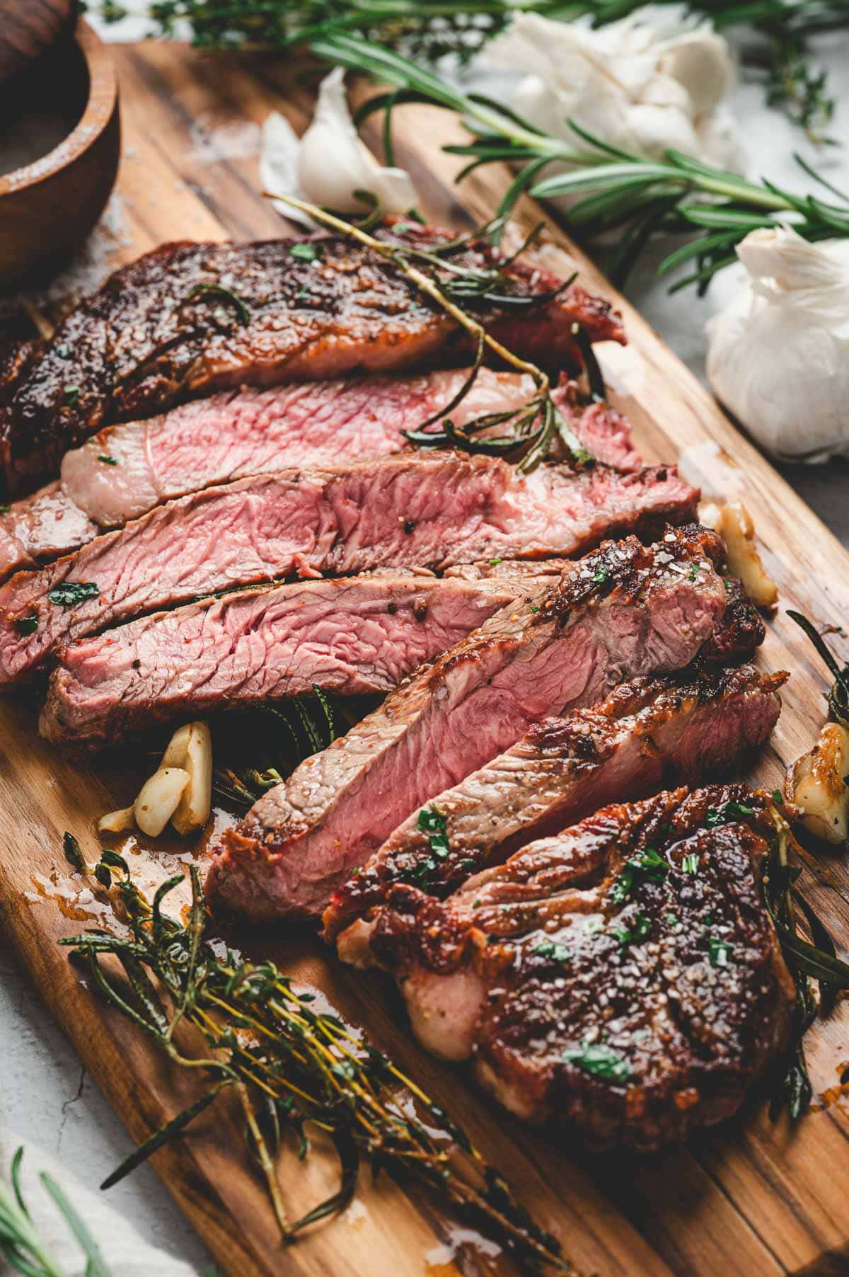 Cutting board with pan seared ribeye steak slices.