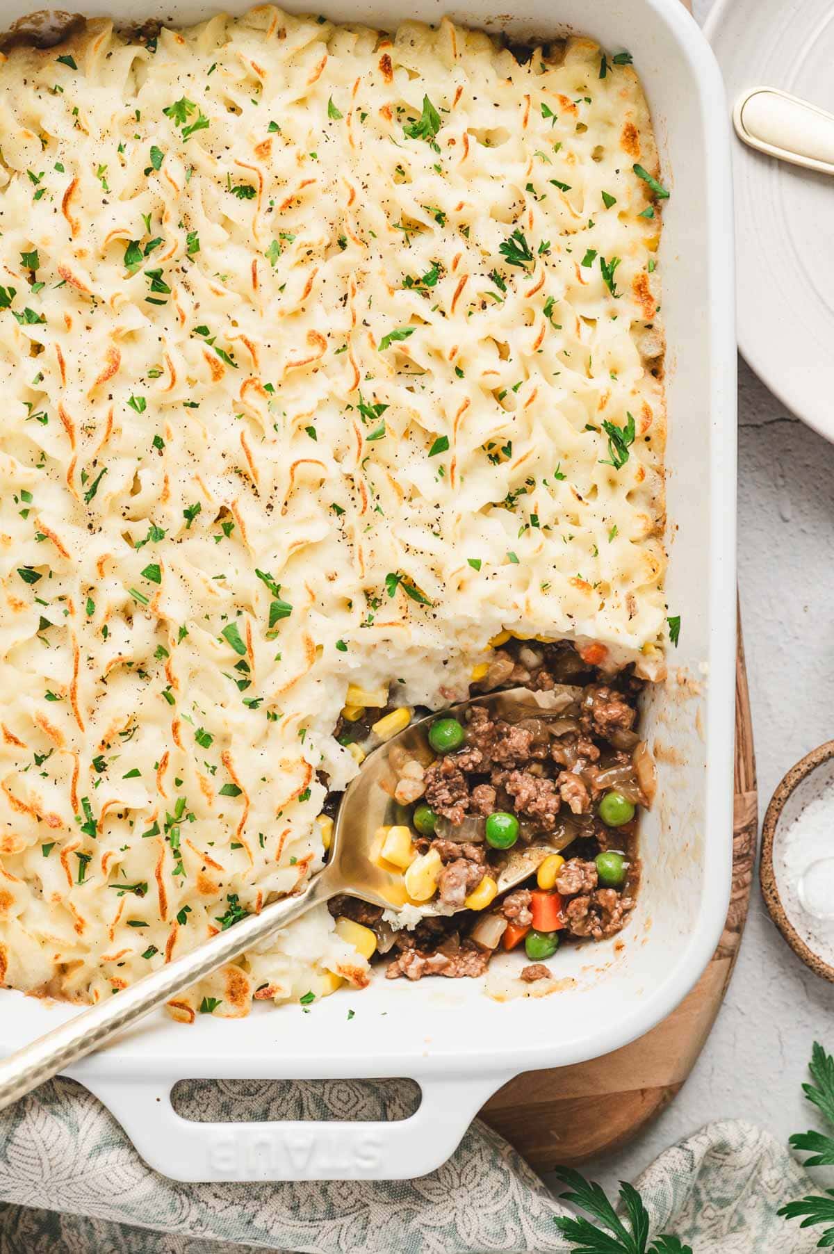 Shepherd's pie in a white casserole dish with a sprinkle of parsley on top.