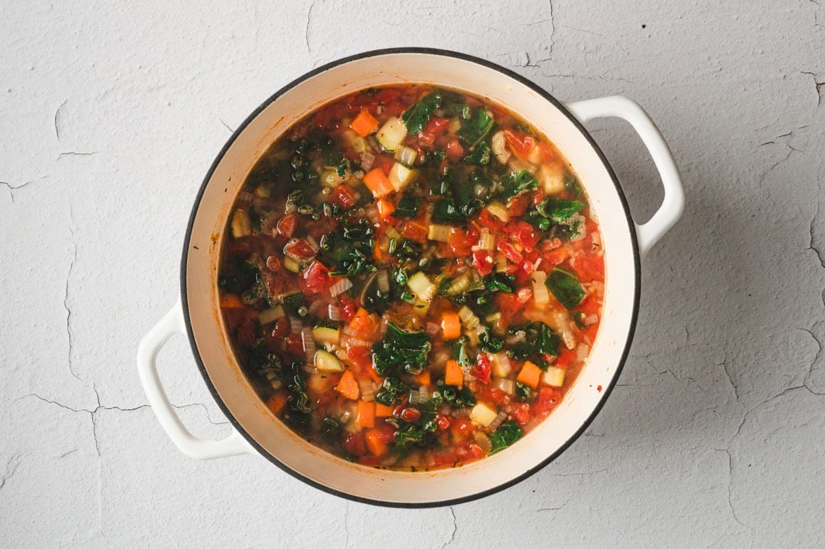 Cooked Tuscan Vegetable Soup in a white enameled pot.