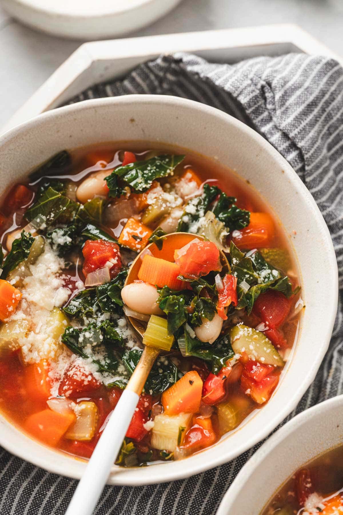 Tuscan Vegetable Soup in a white bowl with a spoon.
