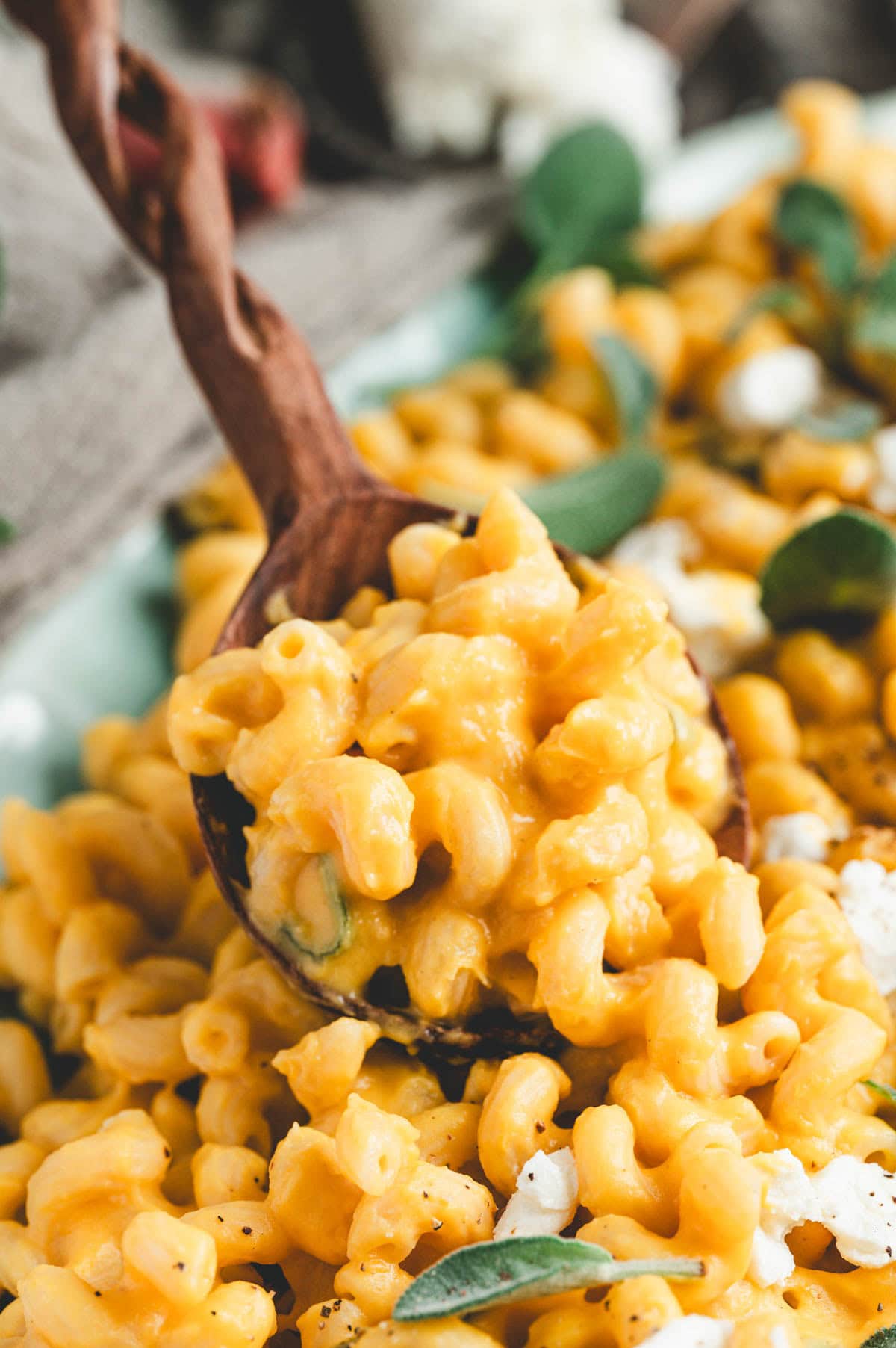 Spoonful of Butternut squash pasta garnished with goat cheese, sage leaves, and black pepper.