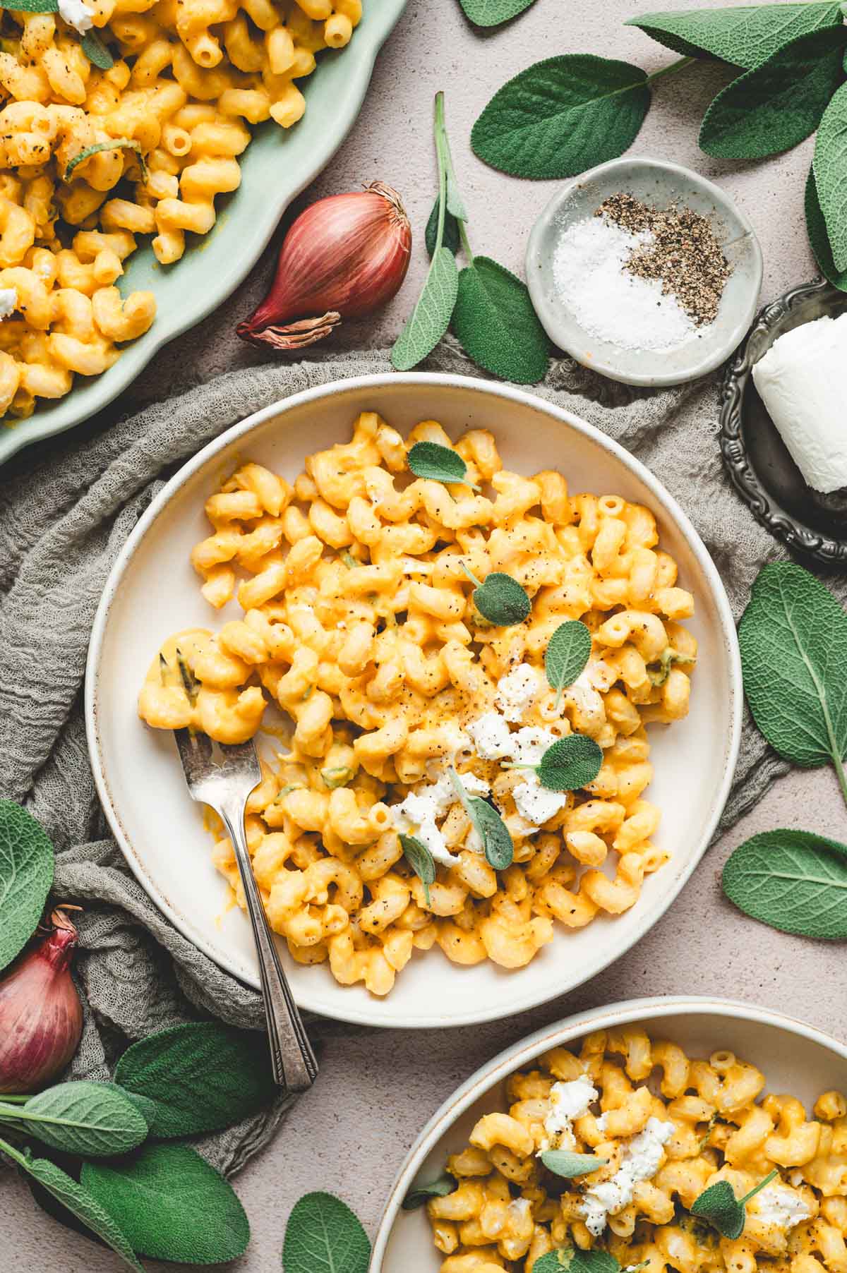 Plate of Butternut squash pasta garnished with goat cheese, sage leaves, and black pepper.