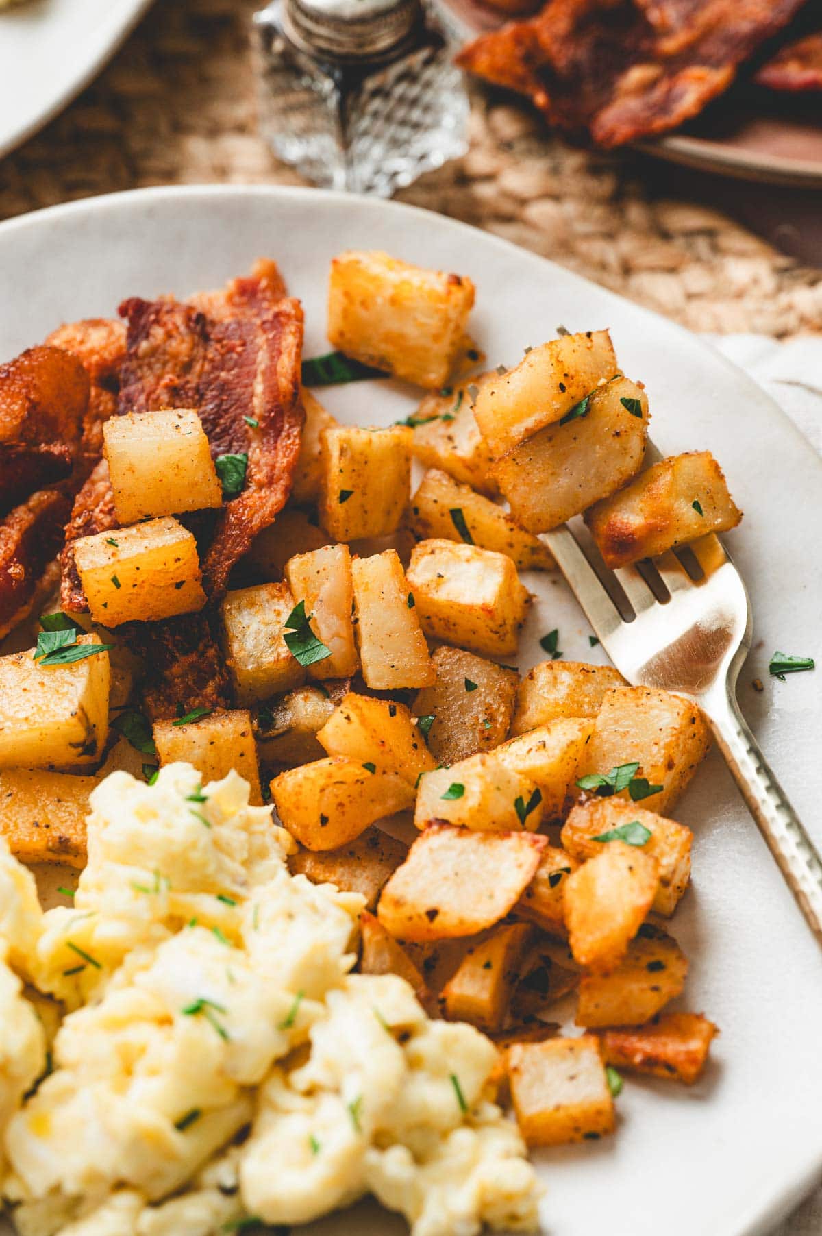 Breakfast potatoes next to scrambled eggs on a plate.