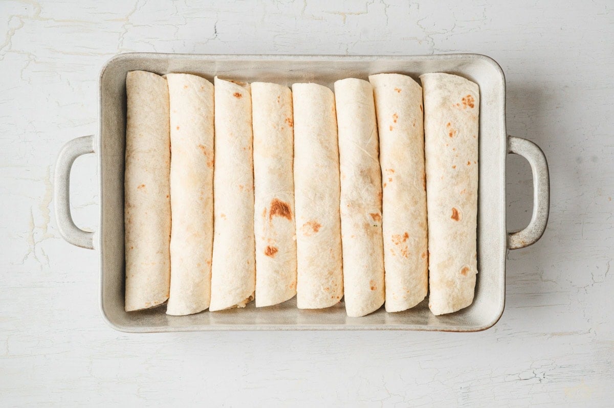 Cranberry turkey enchiladas rolled up in a ceramic dish.