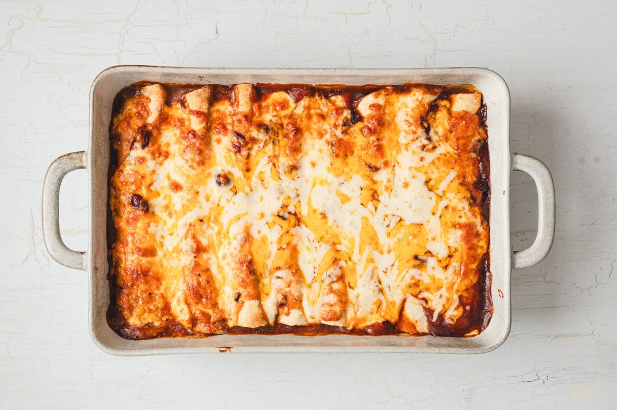 Baked cheesy enchiladas in a ceramic dish.