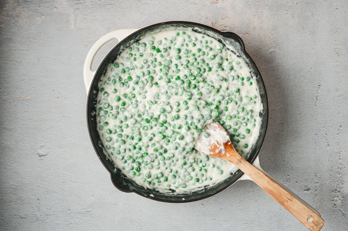 Peas and a cream sauce in a saucepan.