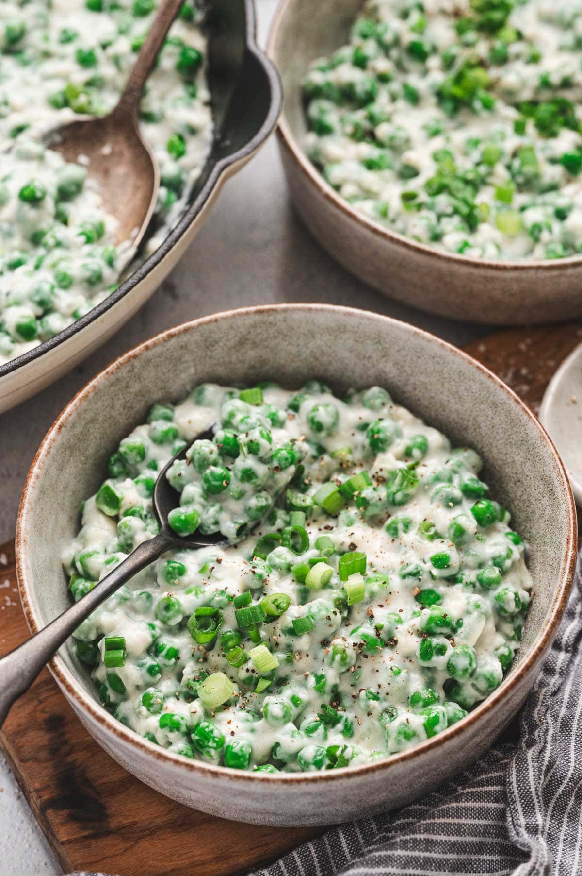 Creamed peas in a ceramic bowl. Garnished with green onions and pepper.