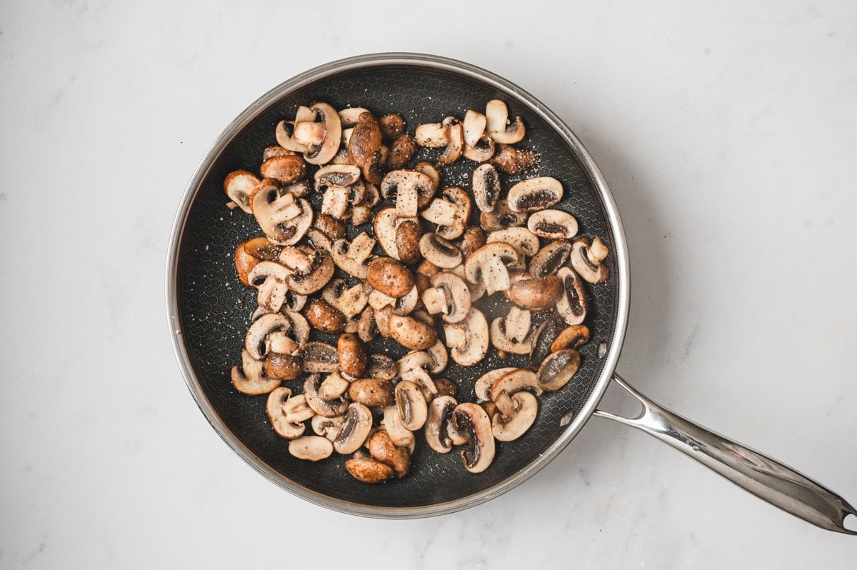 Mushrooms being sauteed in a skillet.