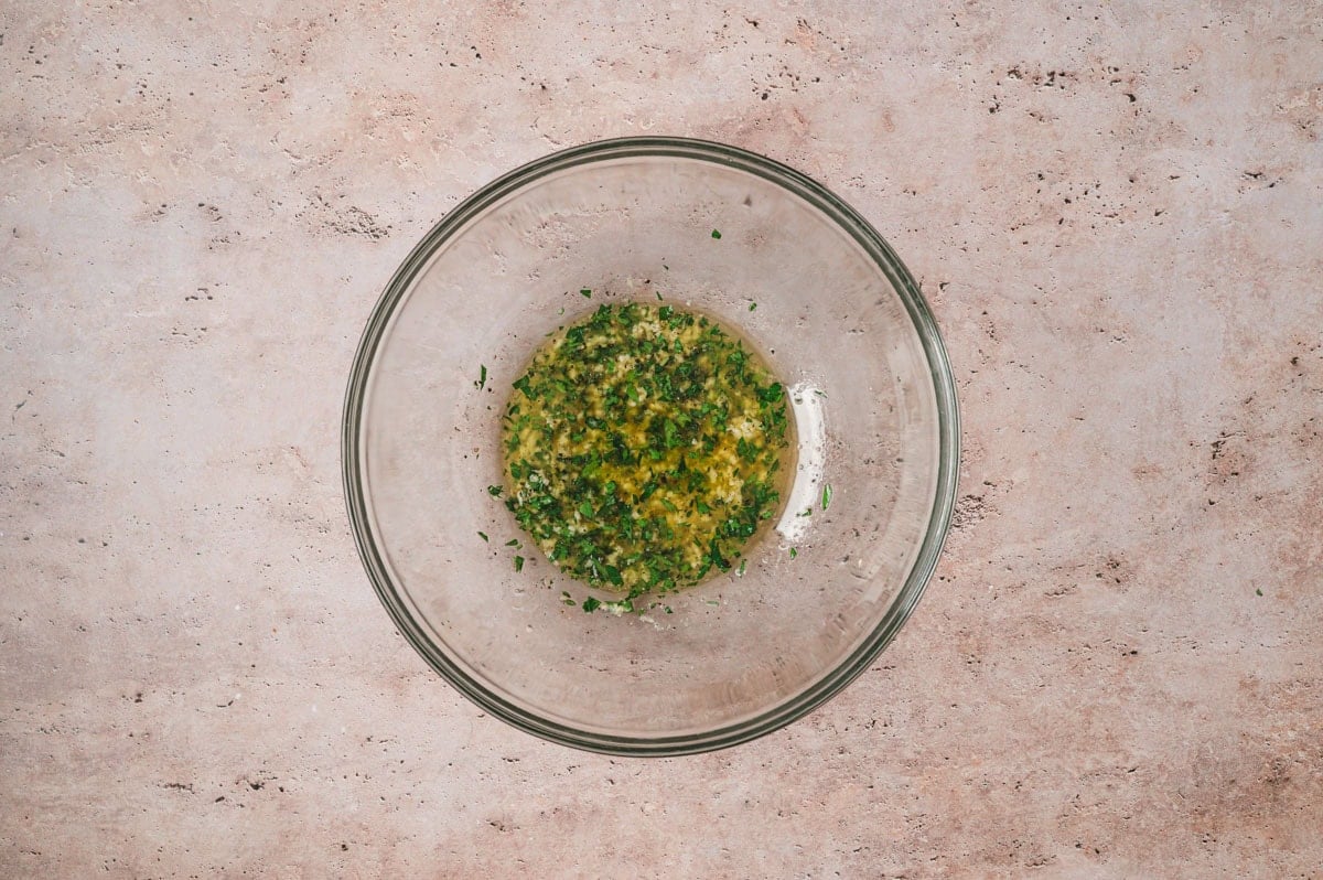 Butter, olive oil, herbs, and garlic in a small glass bowl.