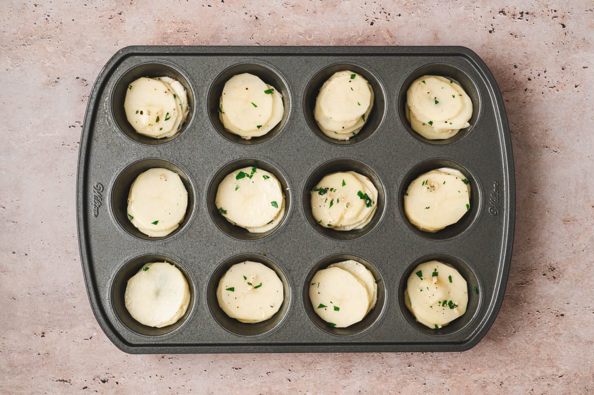 Thin potato slices tossed with garlic, herbs, and butter, layered into a muffin tin.