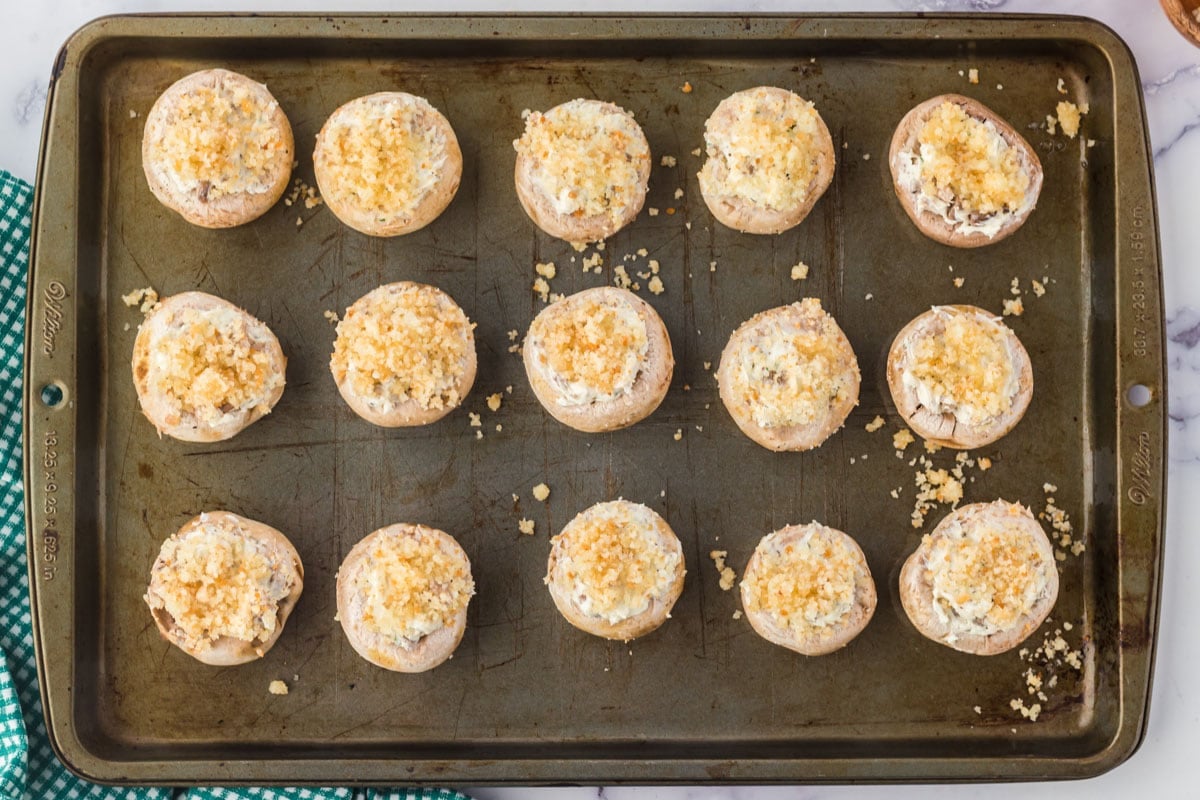 Unbaked stuffed mushrooms on a sheet pan.