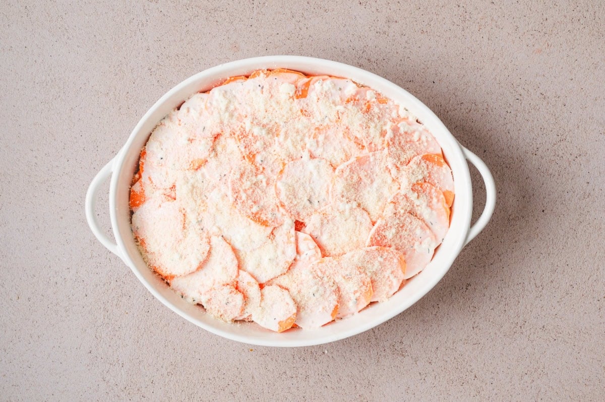 Uncooked sweet potato gratin in a white casserole dish.