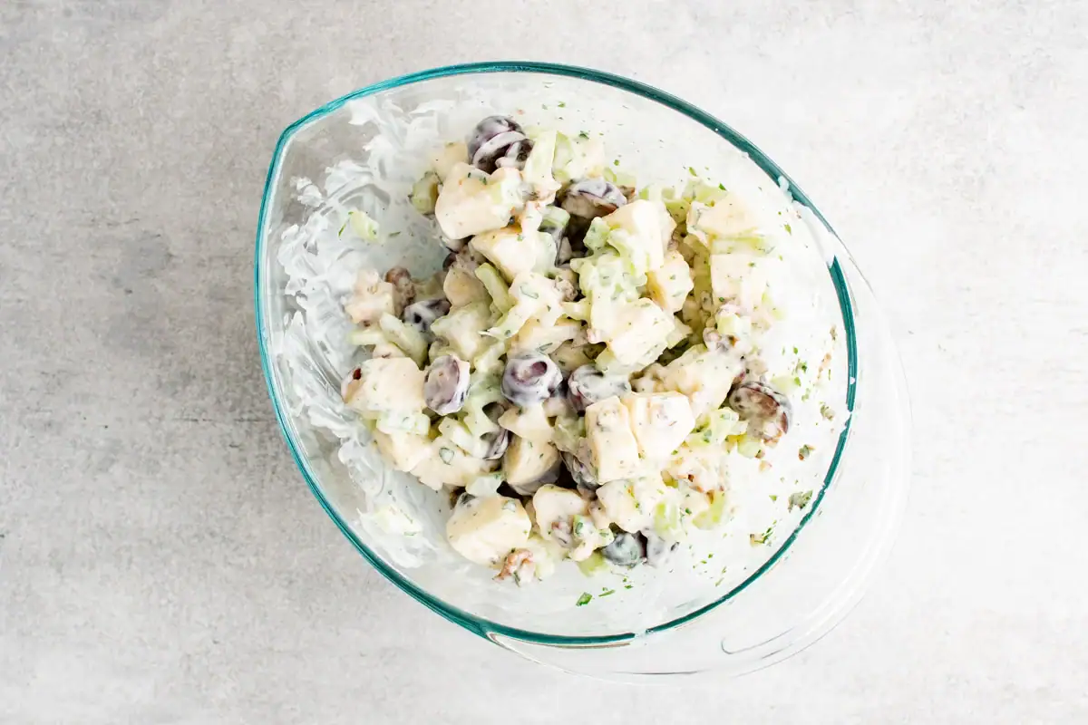 A clear glass bowl with a yogurt dressed Waldorf Salad.