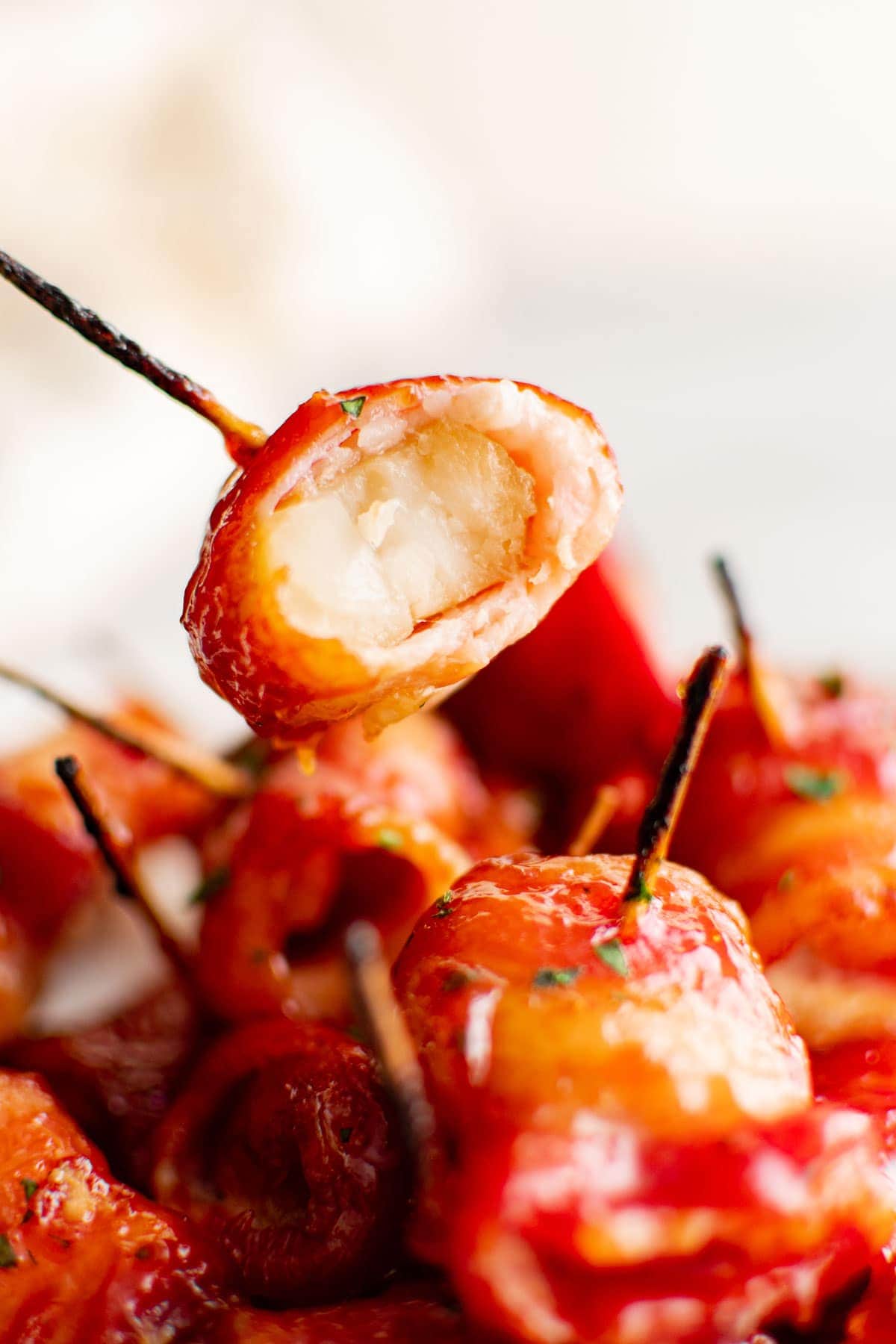 bacon wrapped water chestnuts in a pile, a bite in one