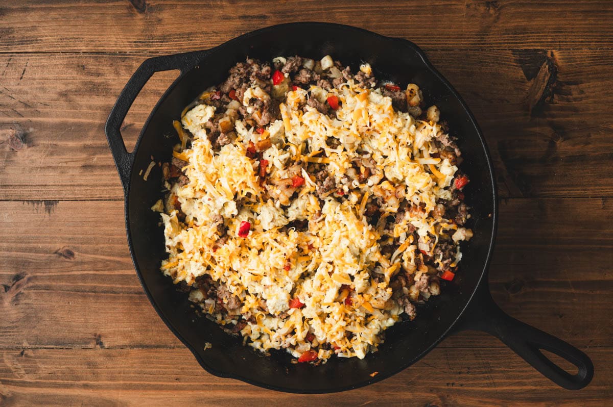 Breakfast hash with scrambled eggs on top in a cast iron skillet.