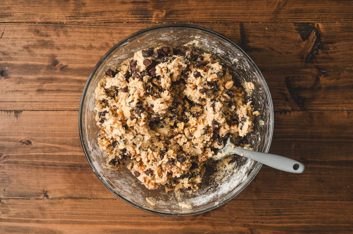 Cookie dough with walnuts and chocolate chips in a glass bowl.
