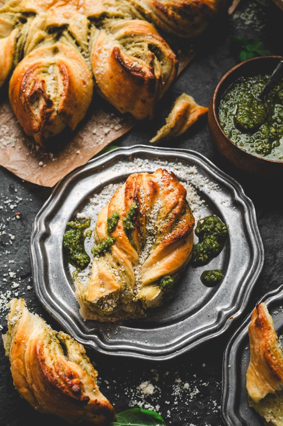 Piece of pesto star bread on a dark grey decorative plate.