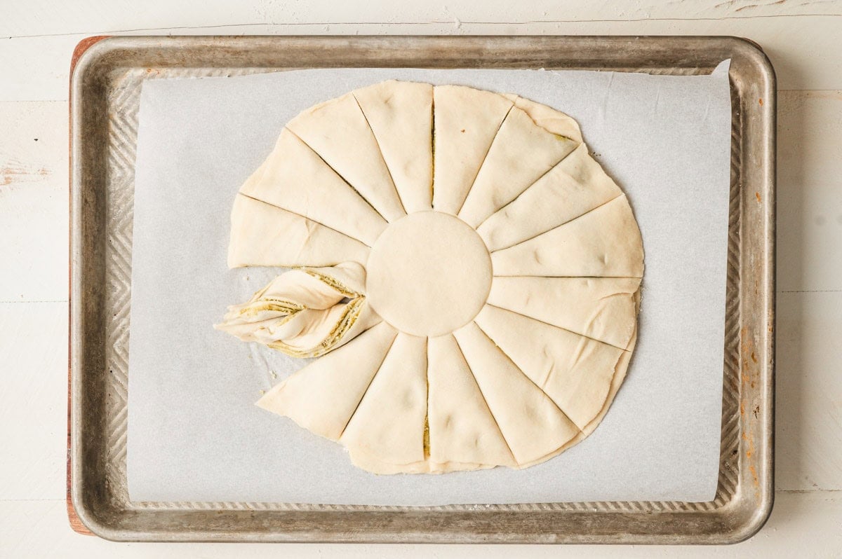 Image showing pesto star bread, cut into pieces, being twisted into the star points.