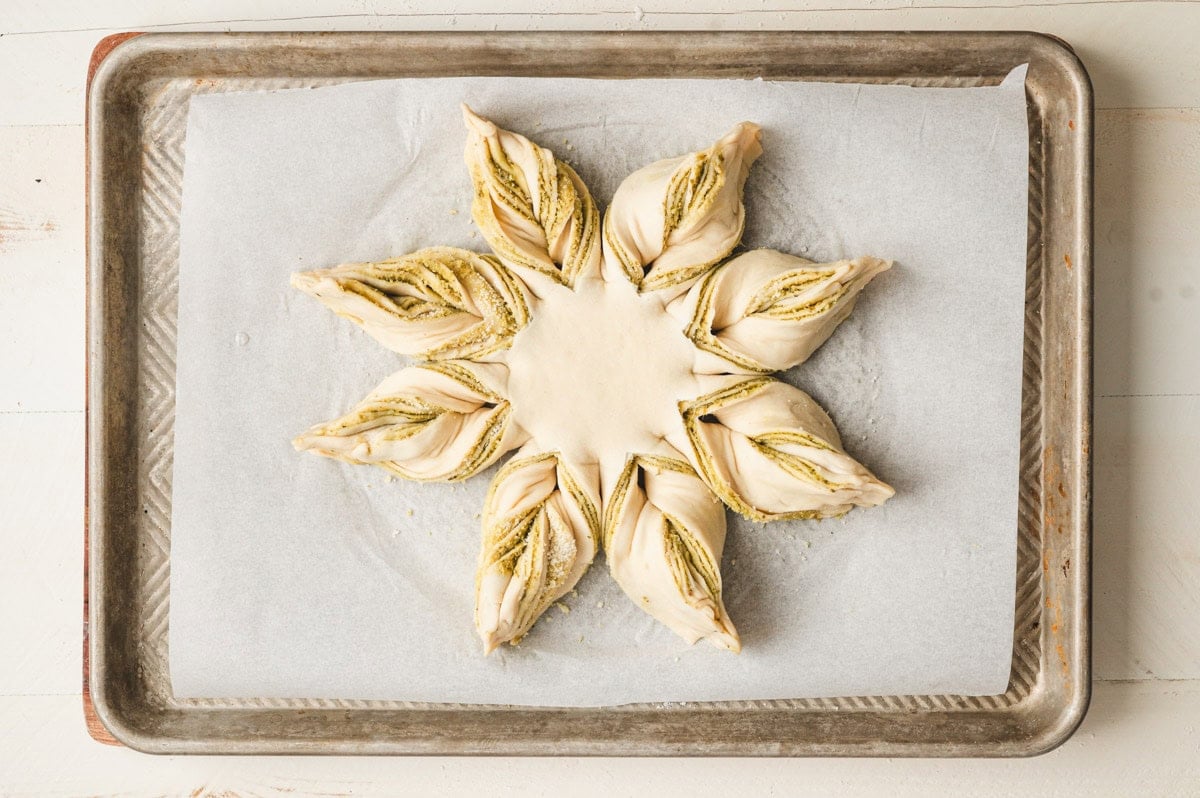 Unbaked pesto star bread on a parchment lined sheet pan.