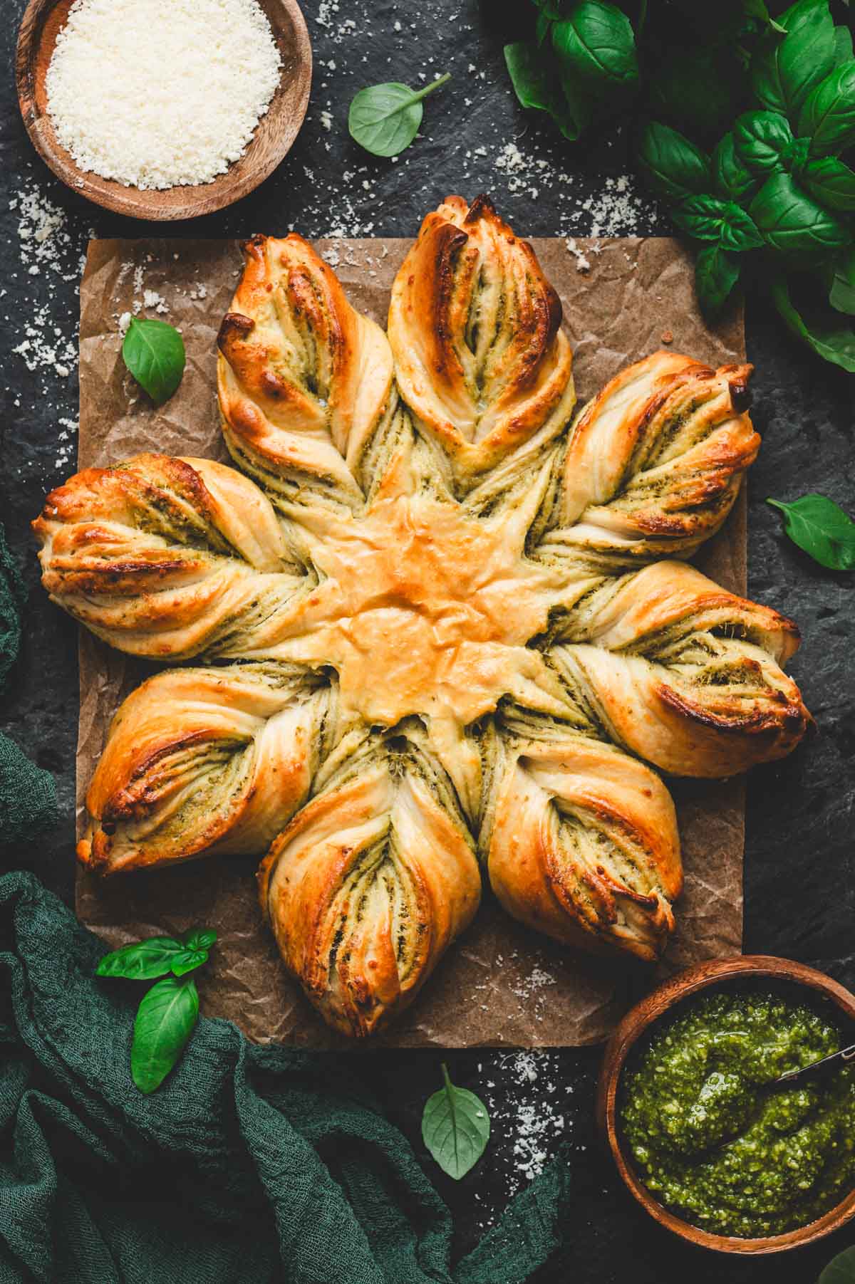 Beautiful 8 point pesto star bread with pesto and fresh basil next to it.