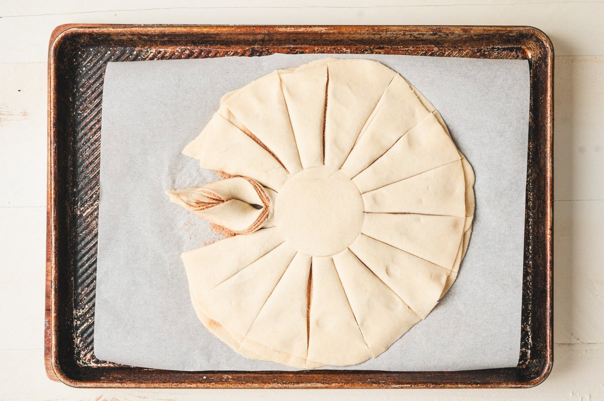 Unbaked star bread dough being twisted into points.