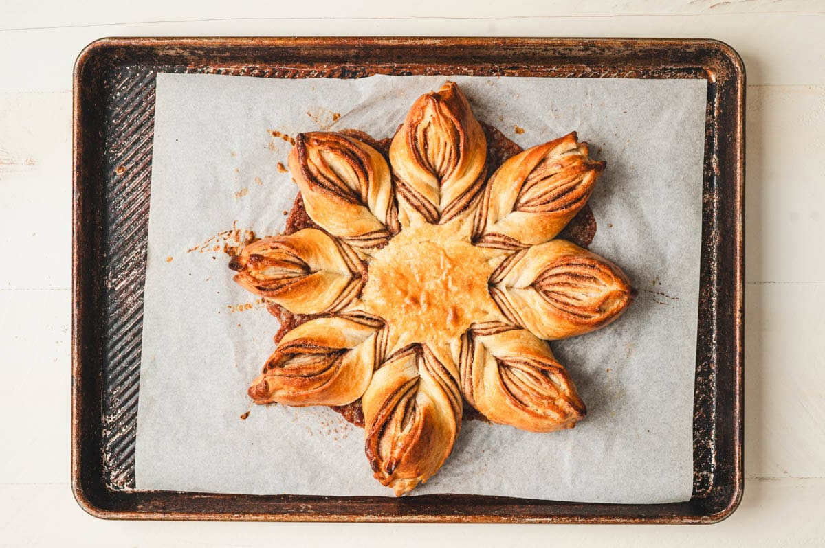 Baked cinnamon star bread dough on parchment paper on a sheet pan.