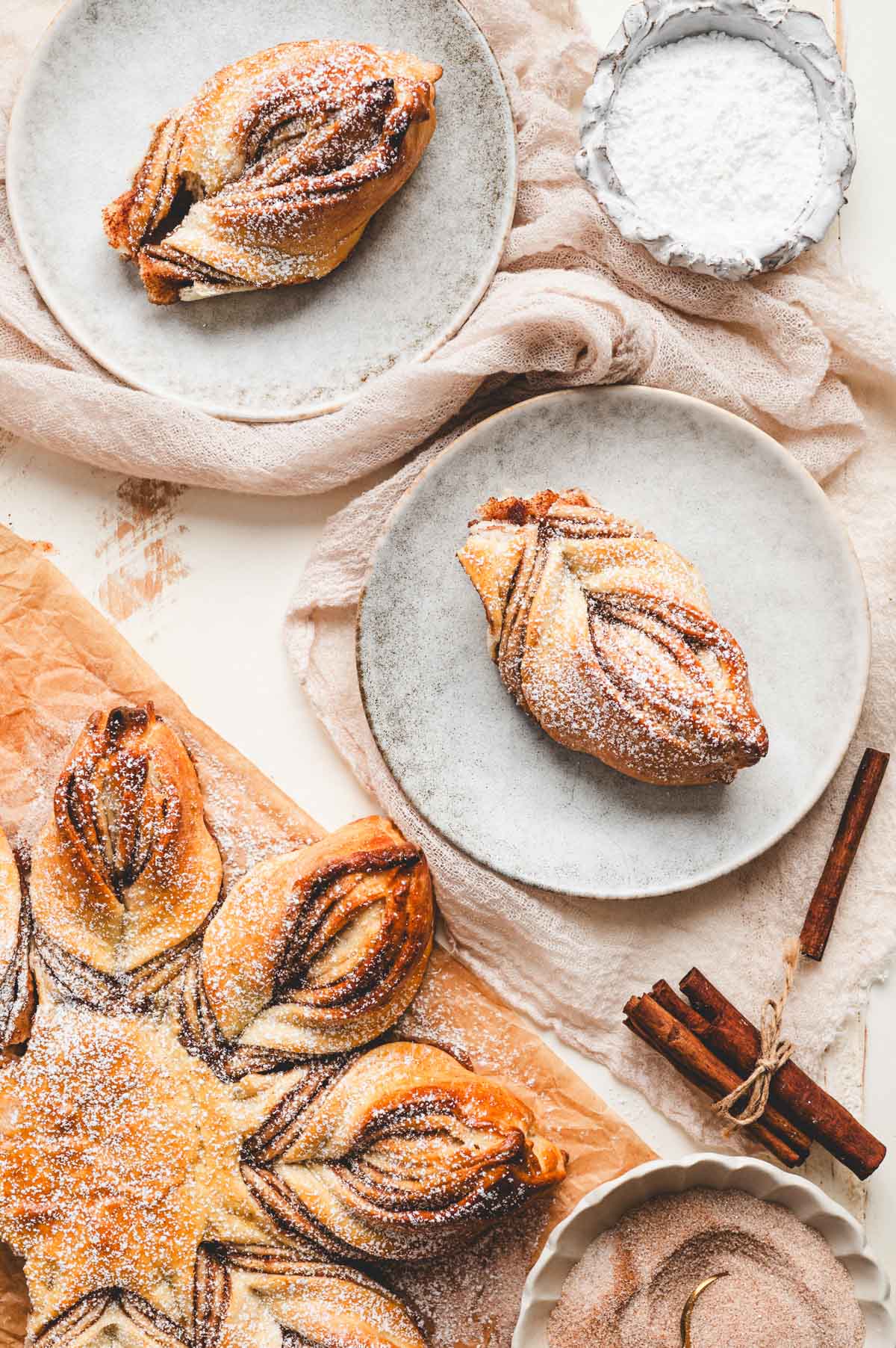 Pieces of cinnamon star bread dusted with powdered sugar on grey ceramic plates.