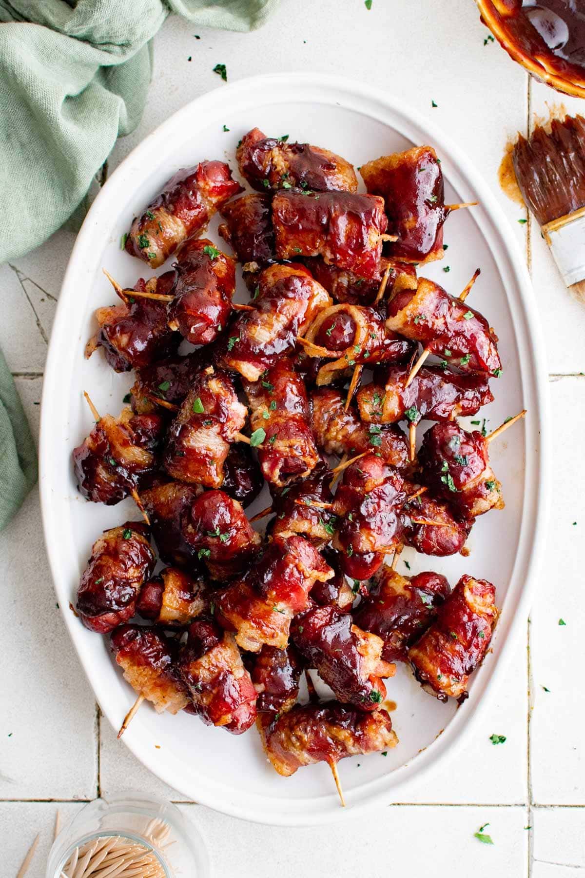 bacon wrapped little smokies with bbq sauce on a white platter