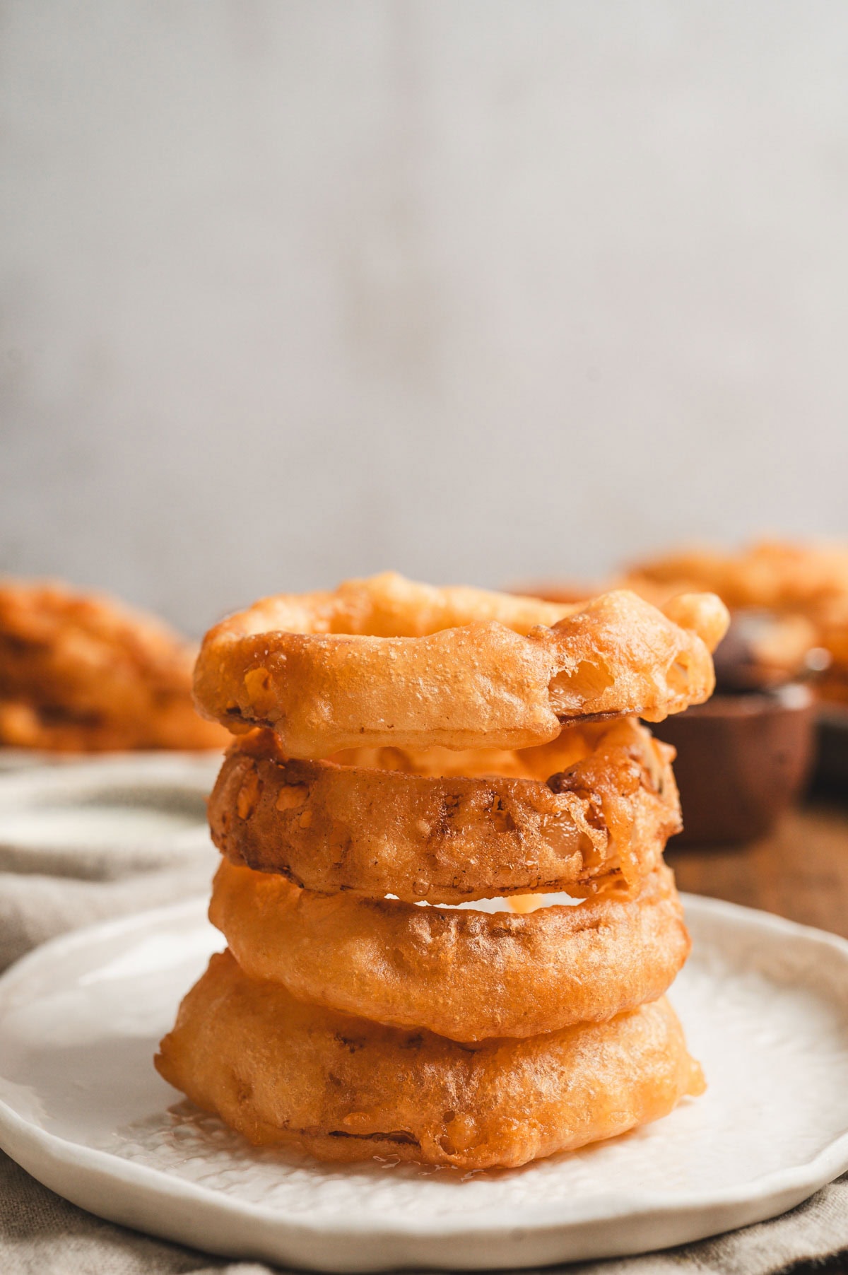 Stack of fried onion rings on a white plate.