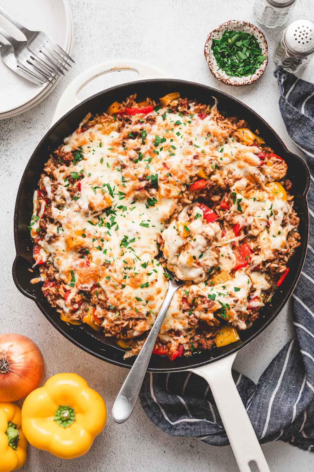 Casserole with ground beef, rice, and bell peppers with cheese on top in a skillet.
