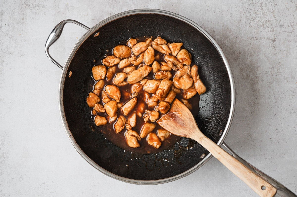 Fully cooked bourbon chicken with sauce in a skillet.