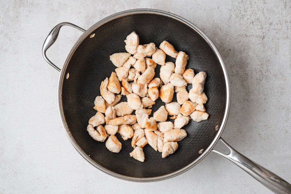 Browned chicken pieces in a skillet.