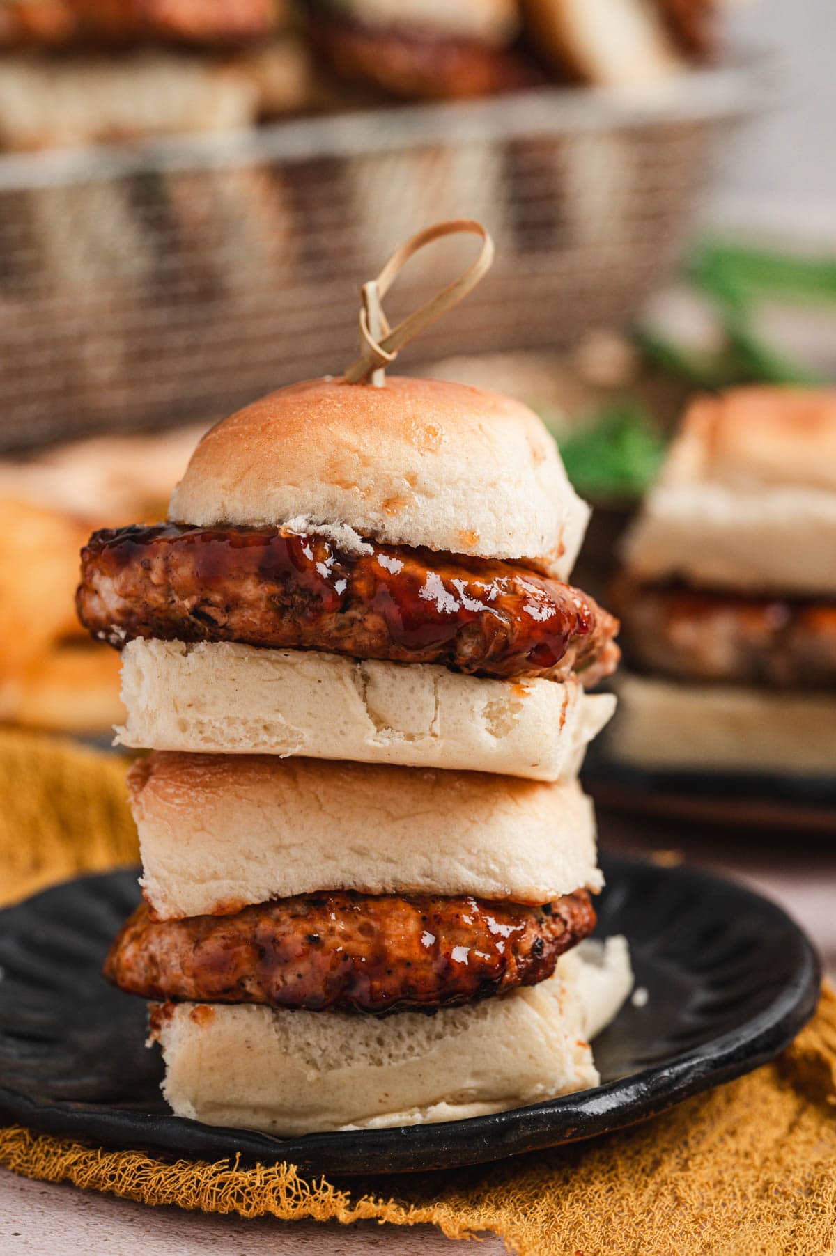 Two Hawaiian pork sliders stacked on top of each other on a black plate.
