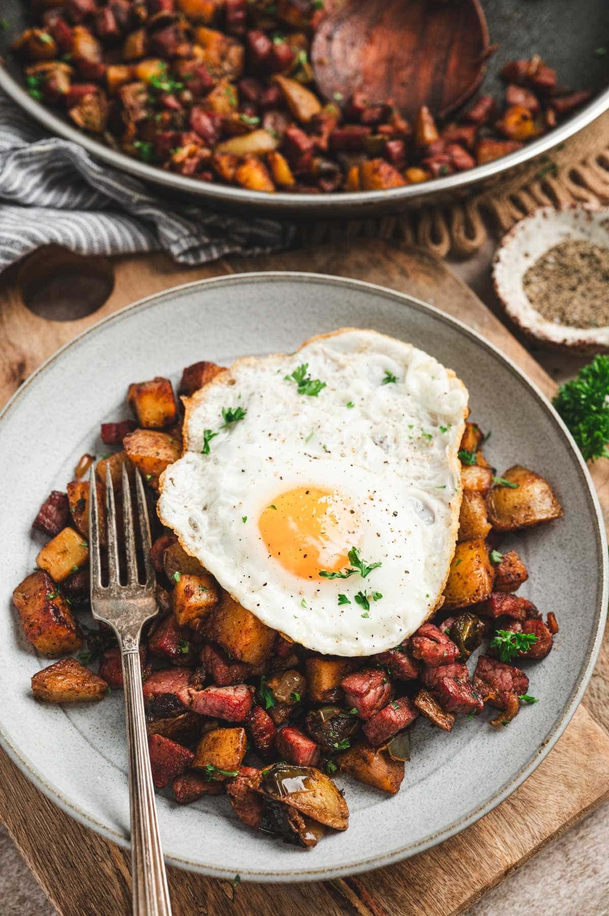 Corned beef hash with a fried egg on top on a plate with a fork.