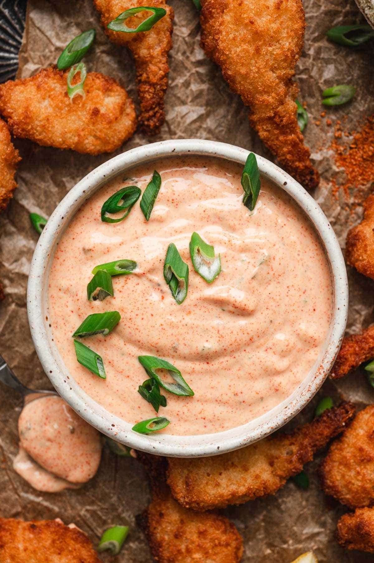 Remoulade sauce in a ceramic bowl with sliced green onions on top.