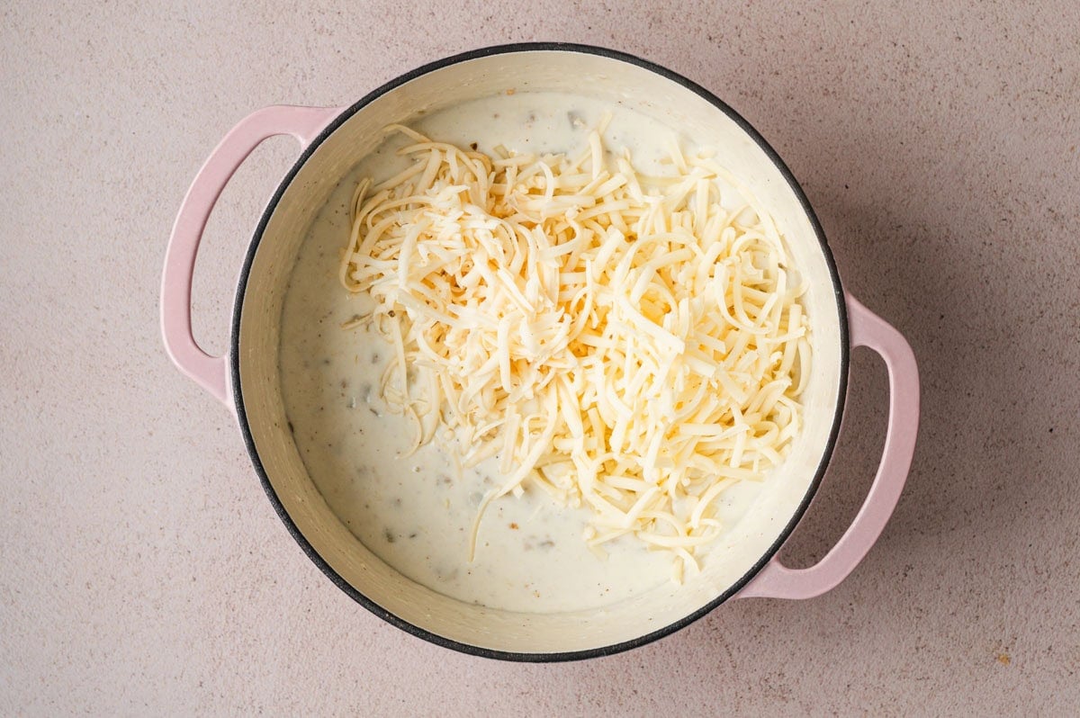 Cheese being added into a mac and cheese sauce.
