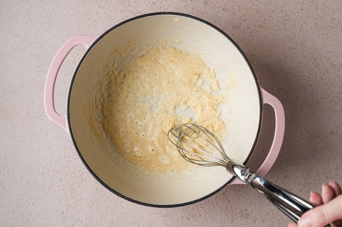 Butter and flour being whisked in a pot.