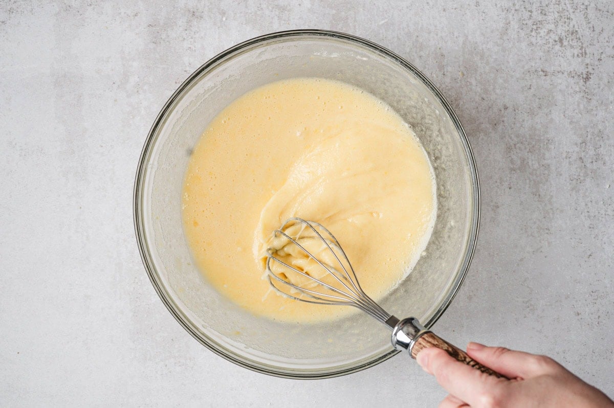 Lemon bar filling being whisked in a glass bowl.