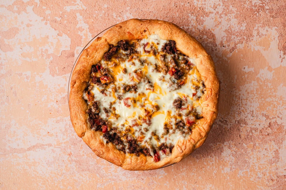 Baked taco pie with golden brown crust topped with ground beef and melted cheese