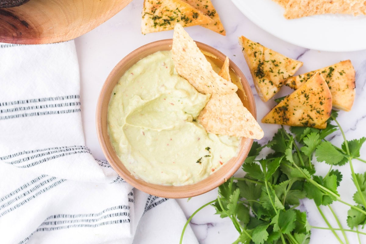 Avocado crema in a bowl with chips.