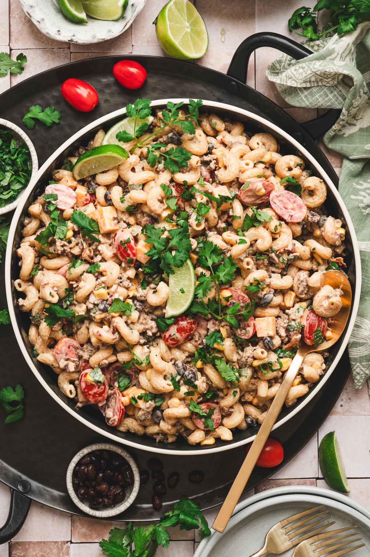 Cowboy pasta salad in a large serving bowl with lime wedge and cilantro garnishes.