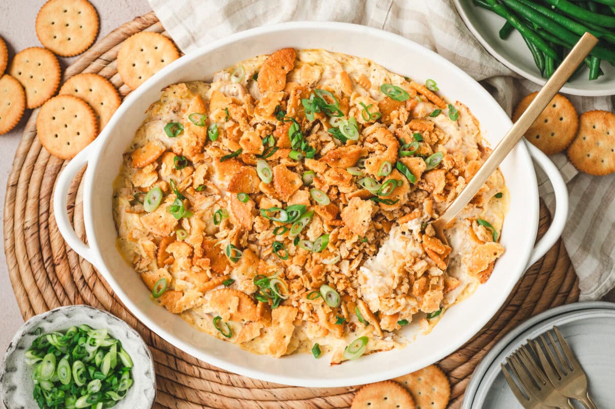 Ritz cracker chicken casserole with green onions on top in a white serving dish.