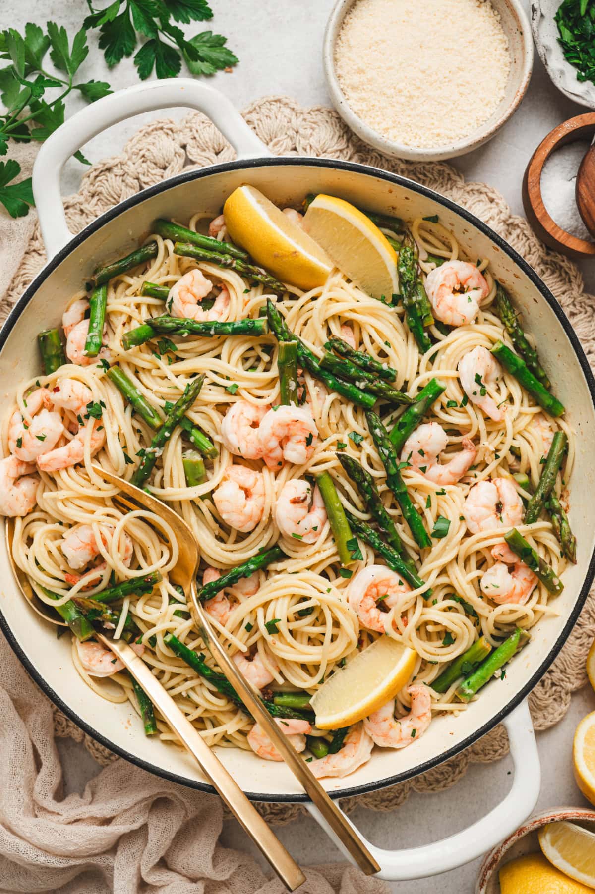 Shrimp and asparagus pasta in a pan with lemon wedges for garnish.