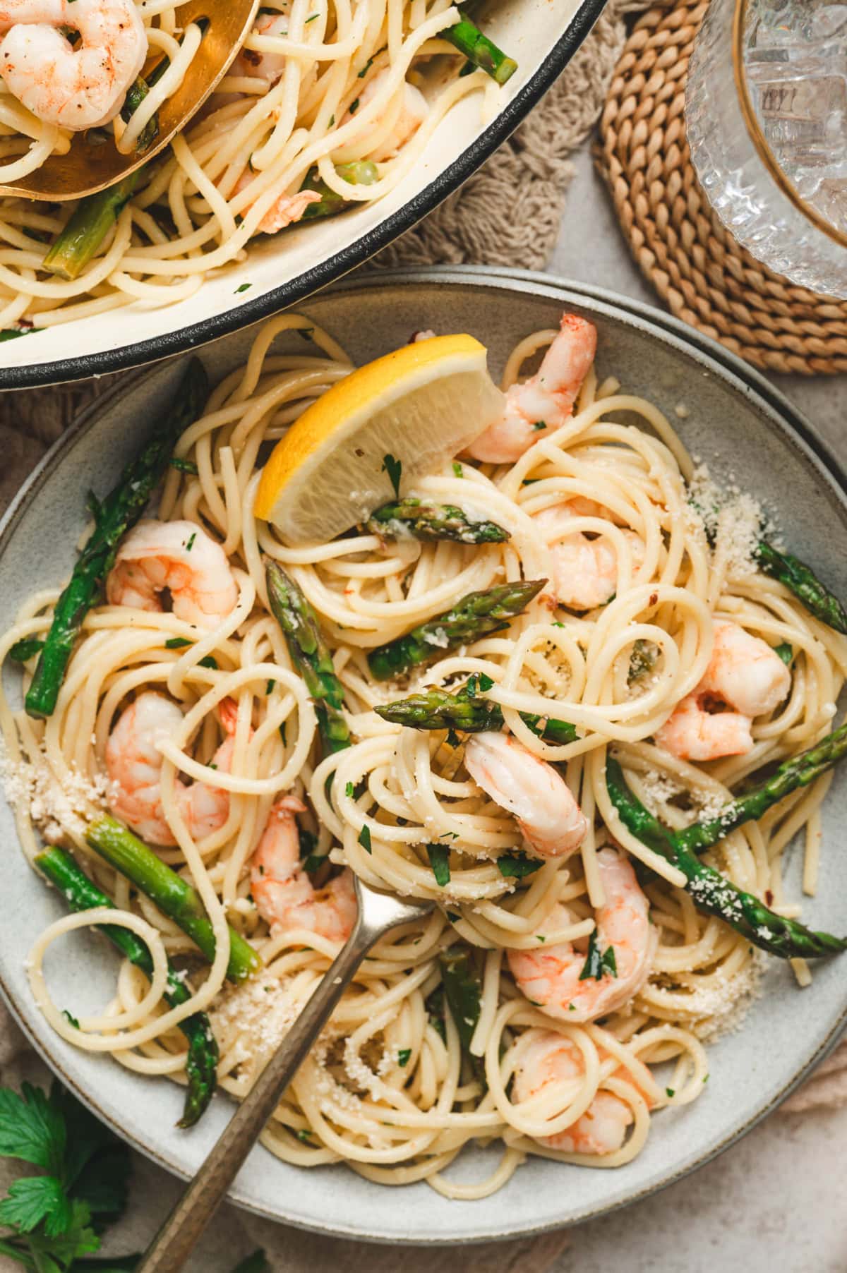 Shrimp and asparagus pasta on a plate with a fork and lemon wedge garnish