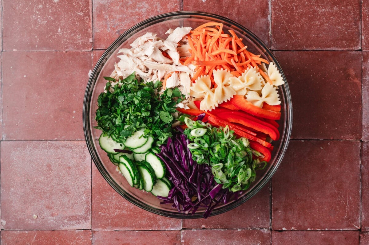 Chopped veggies and shredded chicken in a glass bowl.