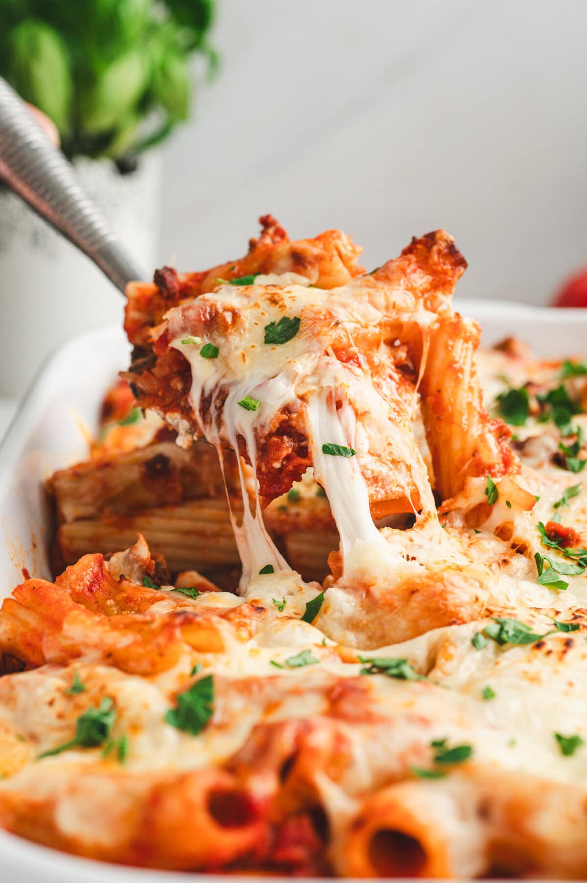 Serving spoon full of cheesy baked rigatoni.