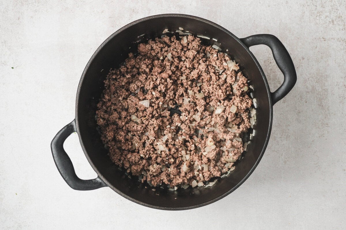 Meat and onions cooked in a black pot.