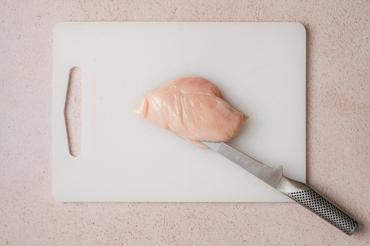 Raw chicken breast being sliced